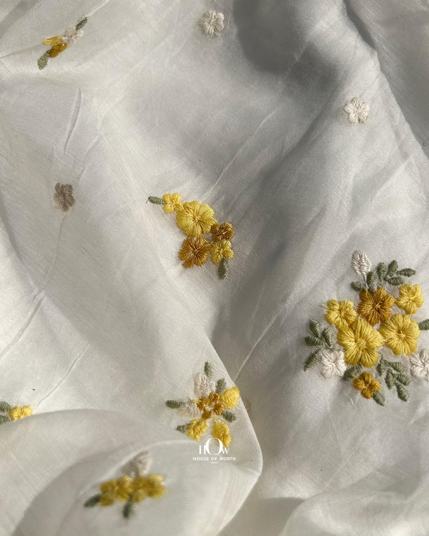 Off-white Mul Chanderi dress material with yellow floral motifs – dyeable fabric perfect for festive tailoring and boutique use.