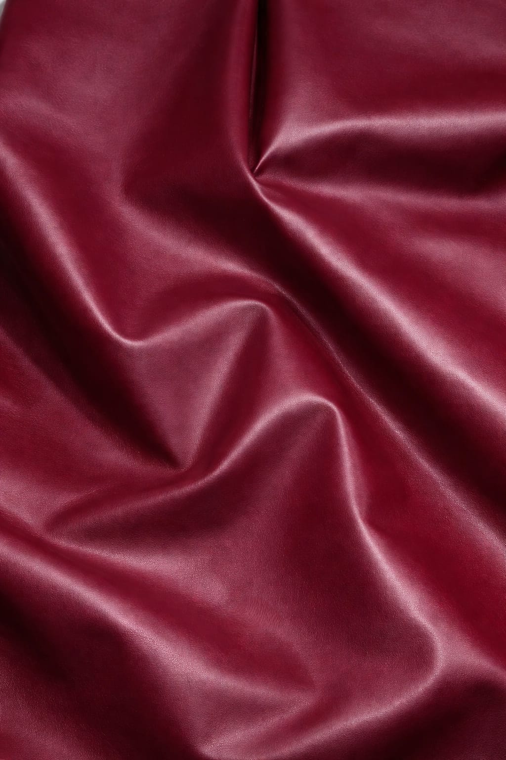 Maroon imported leather fabric close-up with wine-rich sheen for premium jackets and co-ords