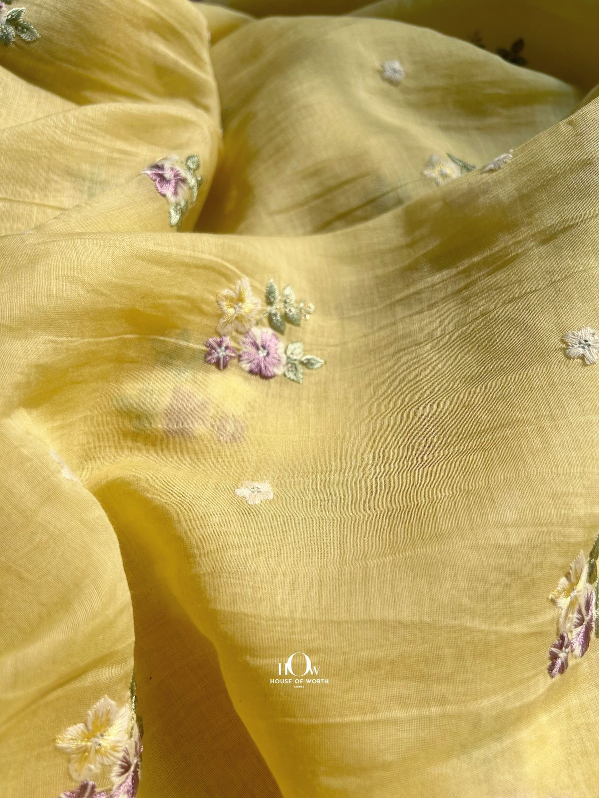 Bright yellow Pure Mul Chanderi fabric with pastel floral embroidery – perfect for festive sarees, kurtas, and suits.