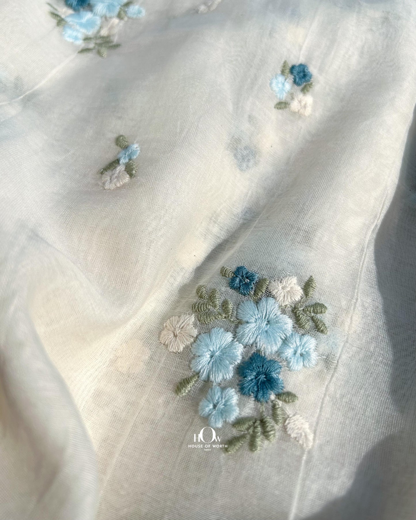Buy dyeable pure mul Chanderi fabric in bulk – handwoven off-white base with threadwork buttas in shades of blue.