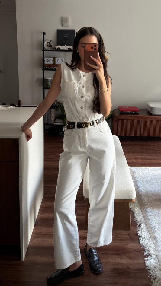 Woman wearing a sleeveless white denim-style button-front top and wide-leg white trousers with a black belt