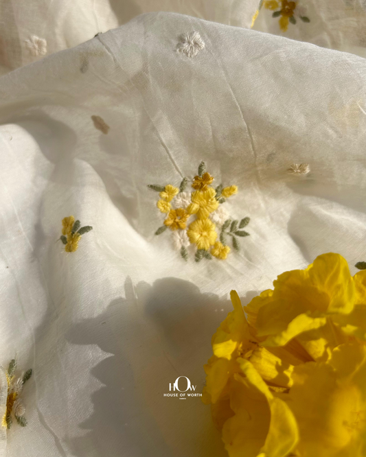Pure dyeable Mul Chanderi fabric in off-white with yellow floral butti embroidery – ideal for sarees, suits, and ethnic dresses.