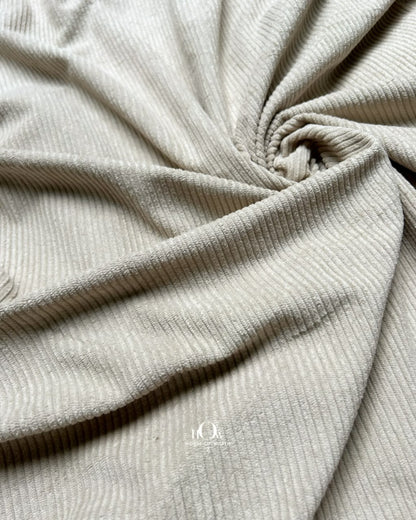 Draped beige corduroy showing distinct ribs and a refined structured appearance
