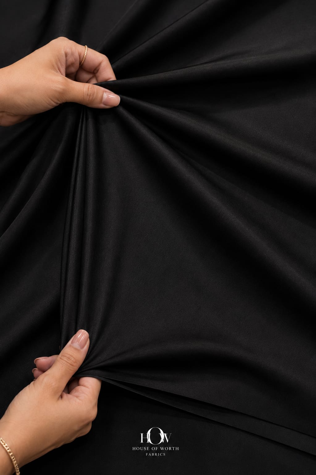Black 4 way Lycra fabric demonstrating flexible stretch across length and width.