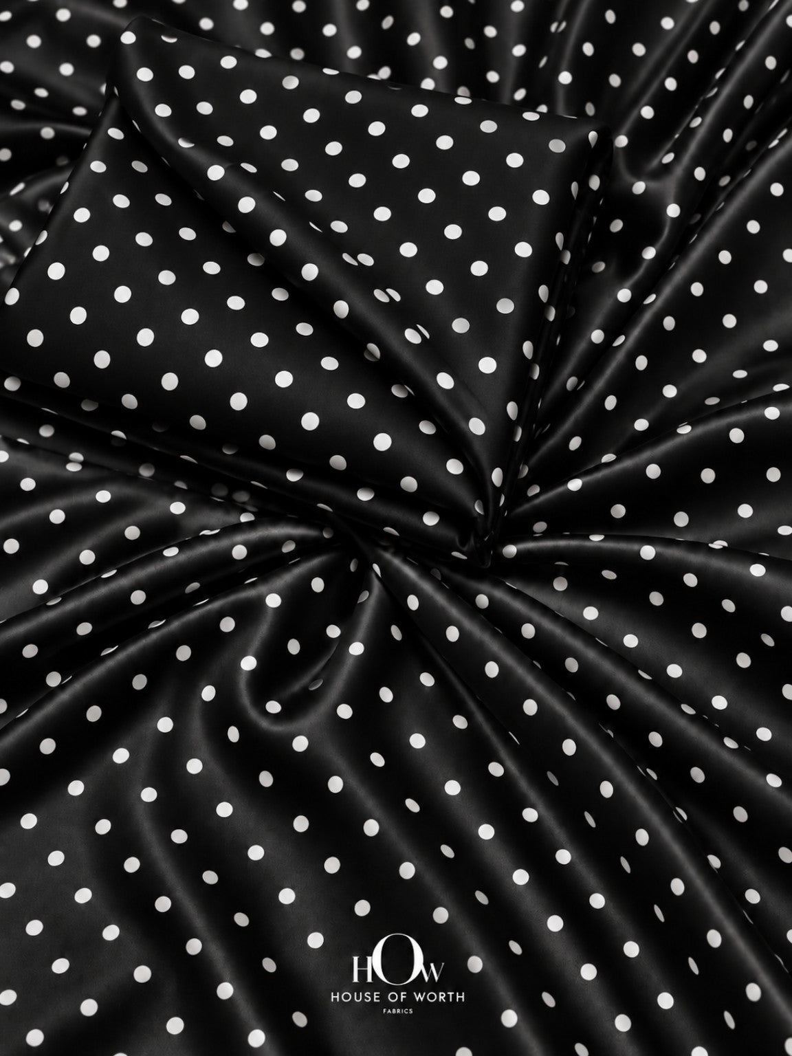 Black polka dot satin fabric with evenly spaced white dots and a smooth satin sheen