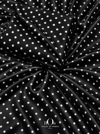 Black polka dot satin fabric with evenly spaced white dots and a smooth satin sheen
