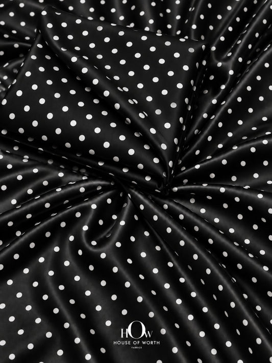 Black polka dot satin fabric with evenly spaced white dots and a smooth satin sheen