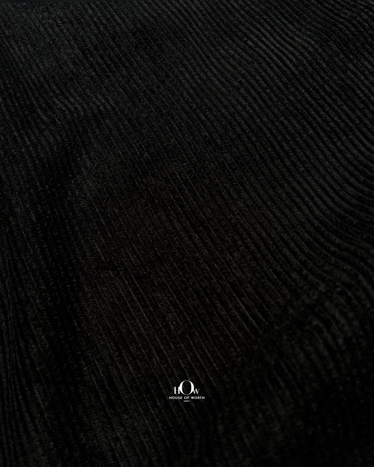 Draped black corduroy showing structured folds and distinct vertical ribs