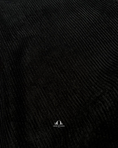 Draped black corduroy showing structured folds and distinct vertical ribs
