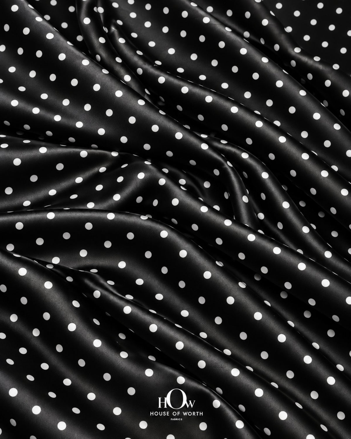 Black satin with crisp white polka dots across a polished, smooth-looking surface
