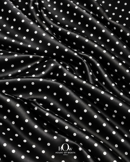 Black satin with crisp white polka dots across a polished, smooth-looking surface