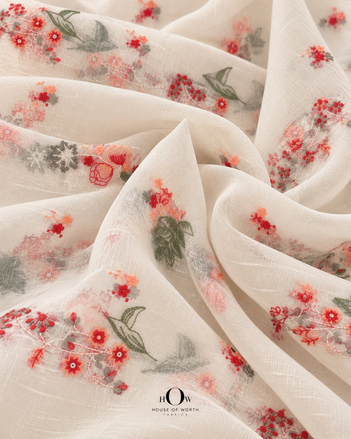 Close-up of coral red and peach floral vine embroidery with muted green leaves on ivory Mul Chanderi