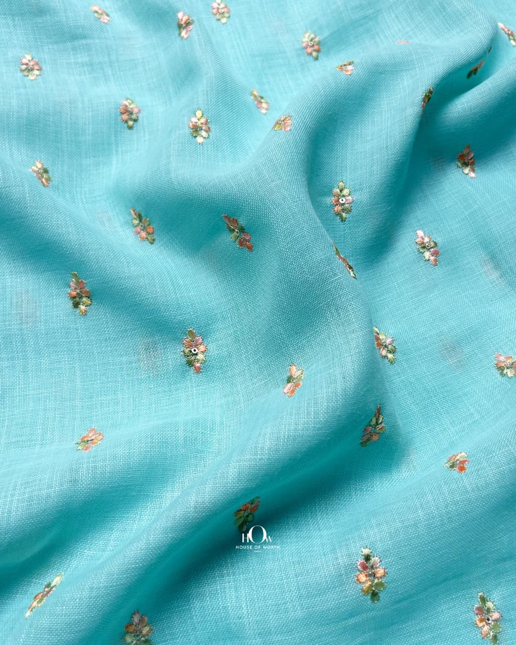 Aqua blue cotton linen fabric featuring intricate floral embroidery for boutique designs.