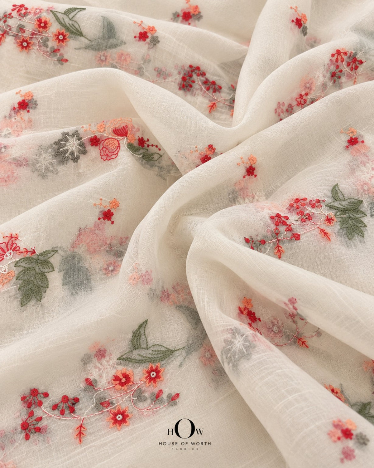 Draped ivory Pure Mul Chanderi showing repeated coral red peach floral vines and botanical sprigs
