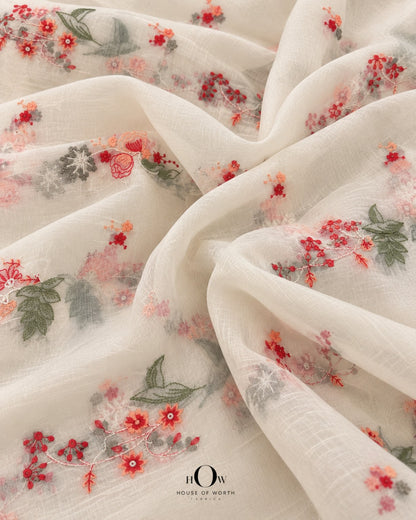Draped ivory Pure Mul Chanderi showing repeated coral red peach floral vines and botanical sprigs