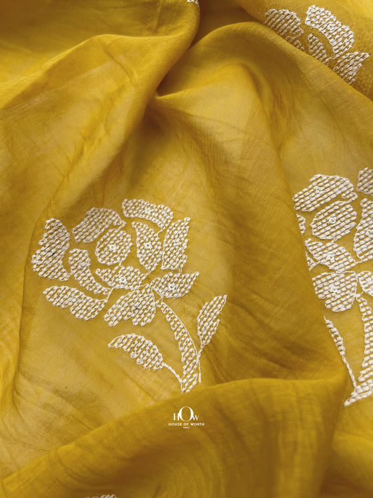 Bright yellow Mul Chanderi fabric with white floral embroidery – perfect for festive sarees, suits, and ethnic wear.