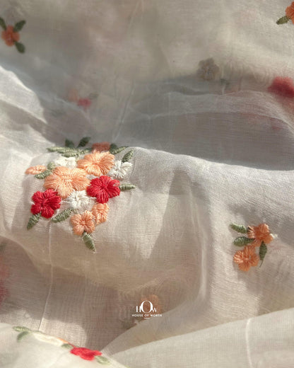 Off-white dyeable Chanderi fabric with small red floral embroidery – suitable for boutique collections and festive tailoring.