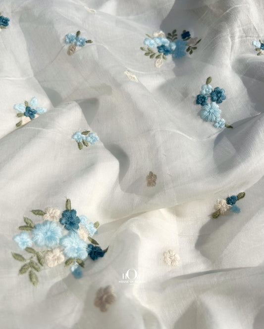 Dyeable Pure Mul Chanderi fabric in off-white with blue floral butti embroidery – ideal for sarees and suits.