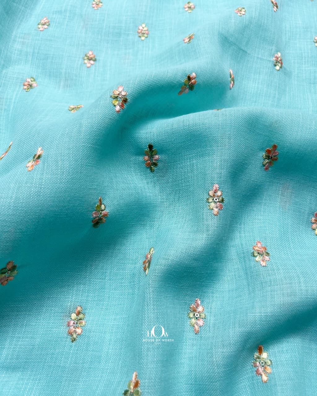 Lightweight aqua cotton-linen blend fabric with embroidered florals for elegant fusion wear.