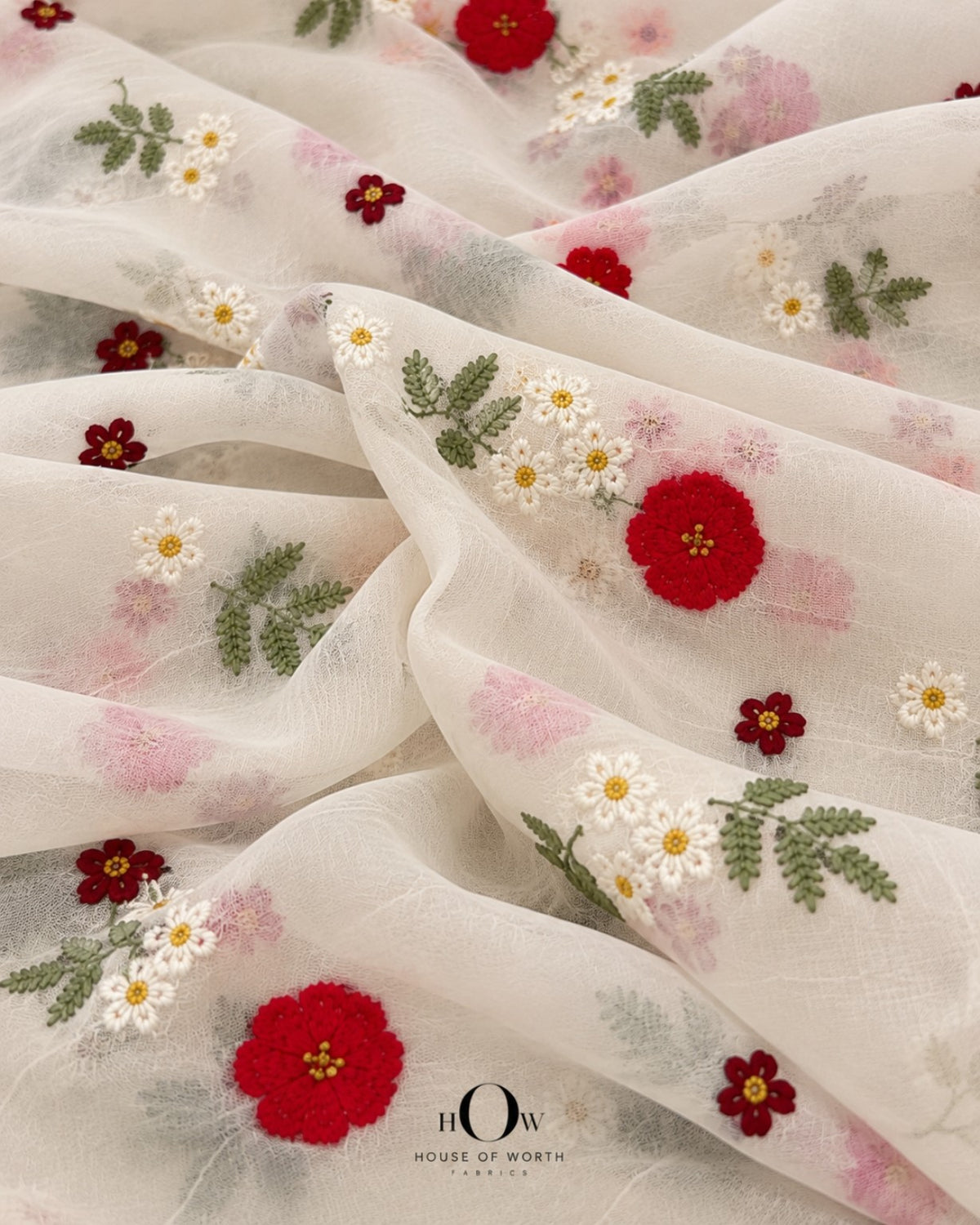 Close-up of red and white embroidered flowers with fern-like green leaves on ivory Mul Chanderi