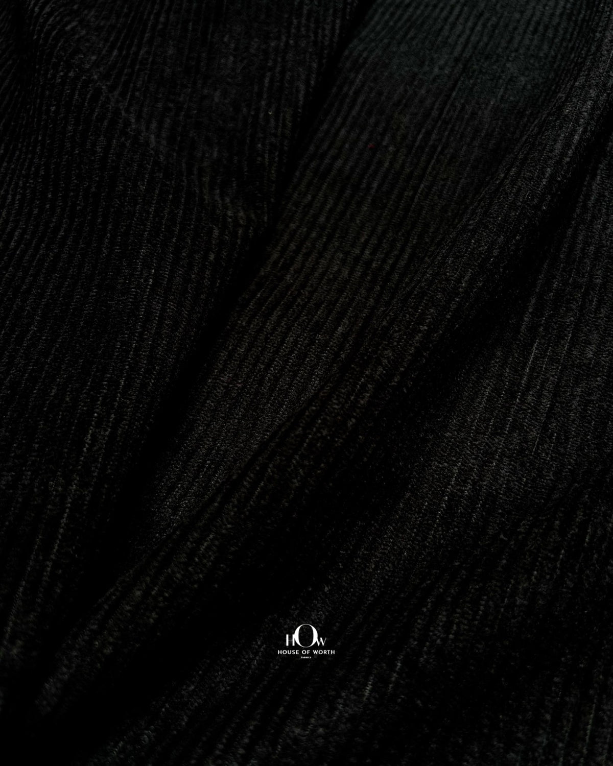 Solid black corduroy fabric with defined ribbed lines for jackets, shirts and trousers