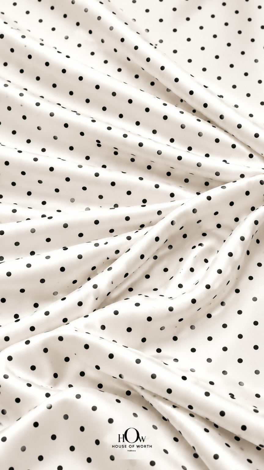 Draped white polka dot satin showing graceful folds and a repeating black dot pattern