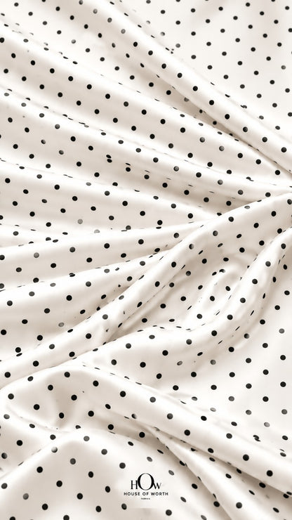 Draped white polka dot satin showing graceful folds and a repeating black dot pattern
