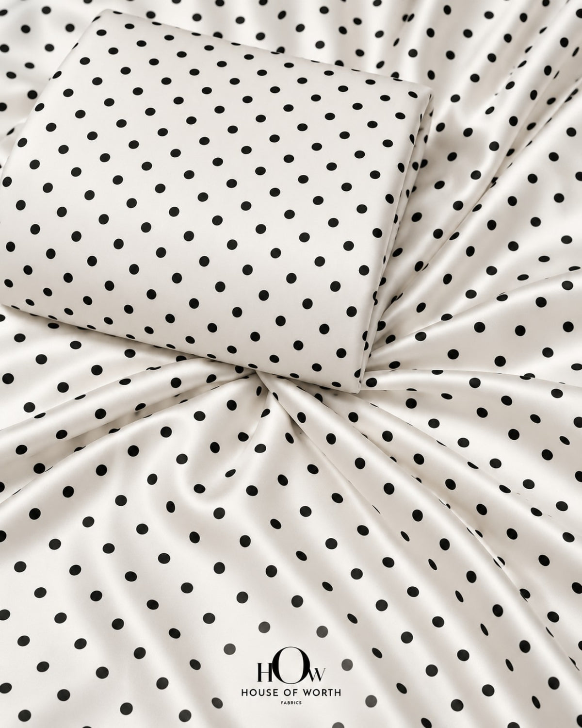 White polka dot satin fabric with evenly spaced black dots and a smooth satin sheen